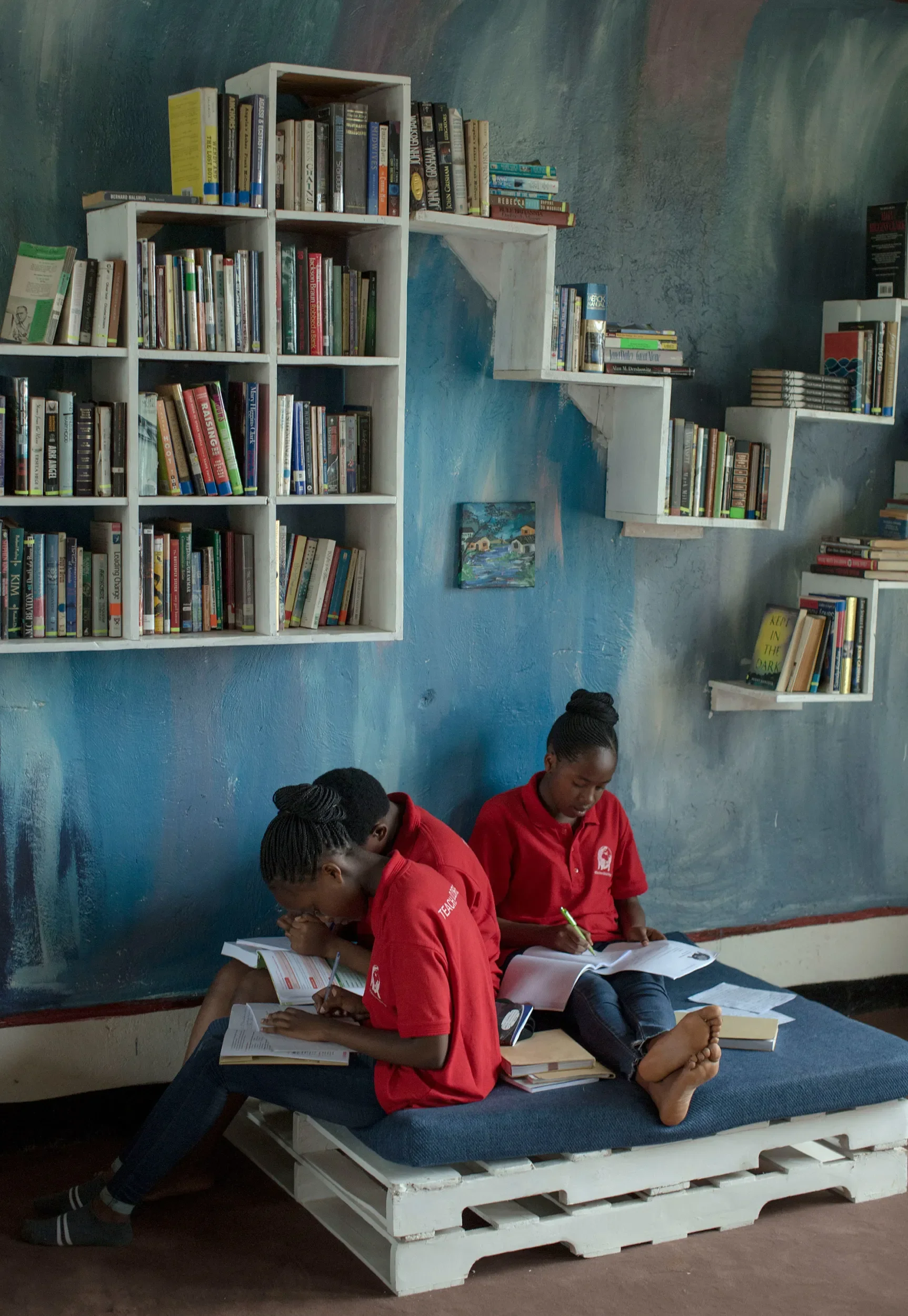 Estudiantes de White Dove Global Prep leyendo en la biblioteca de su escuela. Imagínese que ayudamos a diseñar y abastecer la biblioteca con libros.