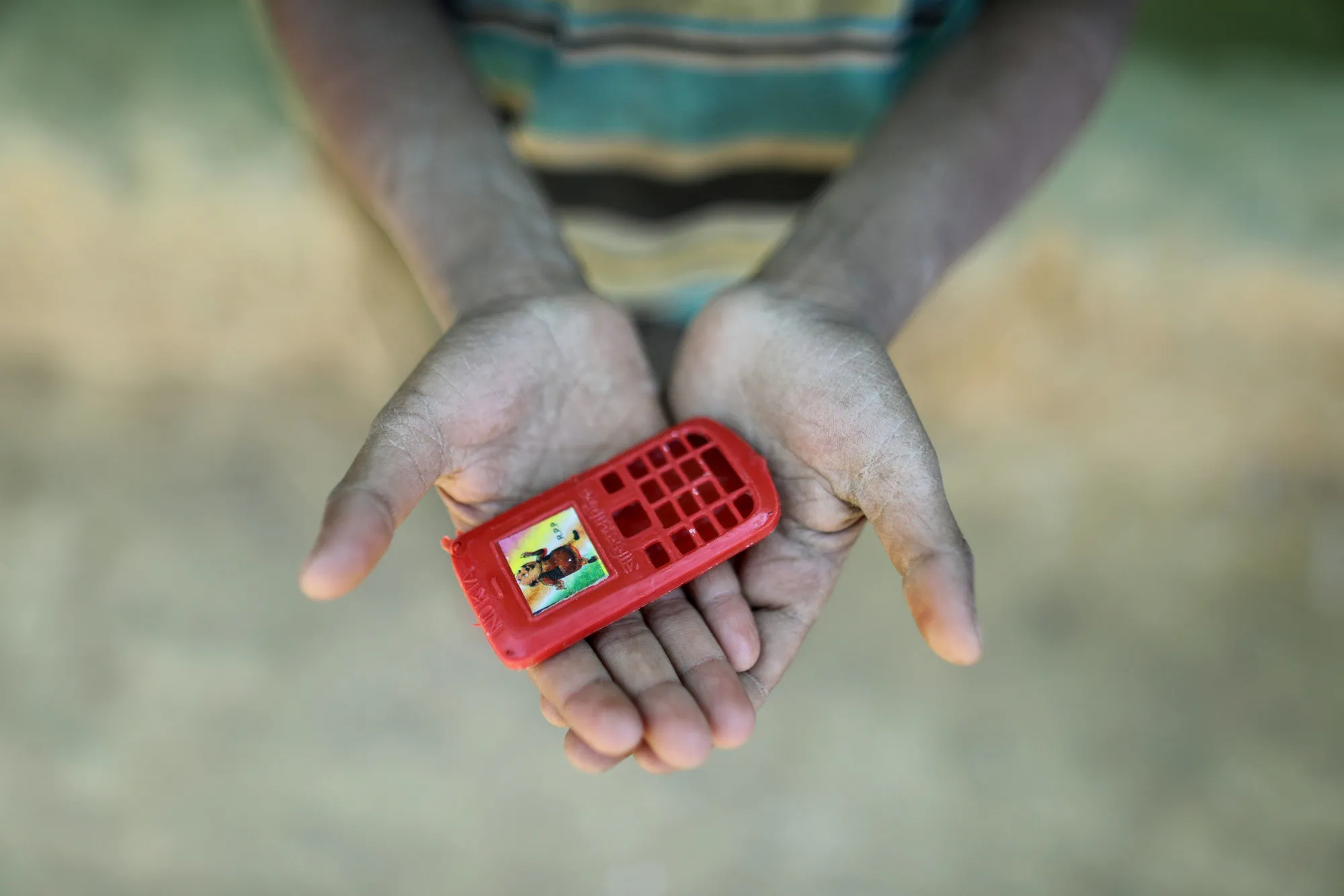 Mohammad found this plastic phone in a snack box he received. The 10-year-old fled Myanmar after his home was burned down. One day he wants to have a real phone to call his friends.
