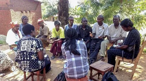 Um grupo comunitário de mulheres e homens, membros de uma Associação de Poupança e Empréstimo de Aldeia, reúne-se em uma aldeia em Burundi, onde VSLAs empoderam economicamente os membros para assumir o controle de suas finanças e futuro.
