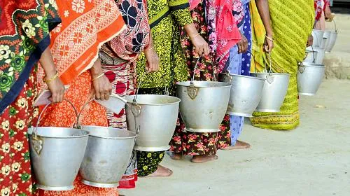 Women from Boithavanga Milk Producing and Marketing group of SDVC II project waiting with their milk pot to sell the milk in Boithavanga Digital Fat Testing milk collection point jointly operated by CARE and BRAC.