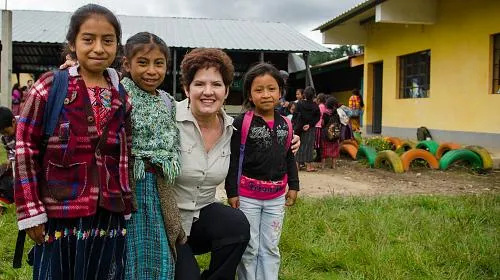 CARE supporter Lynn Jeffords poses with students at the Escuela Oficial Rural Mixta Los Planes, a school participating in CARE's Qach'umilal (Guiding Star) Girls project. The project promotes reducing gender inequality gaps supporting educational models for indigenous children and adolescents living in Santa Lucia Utatlán, Guatemala.