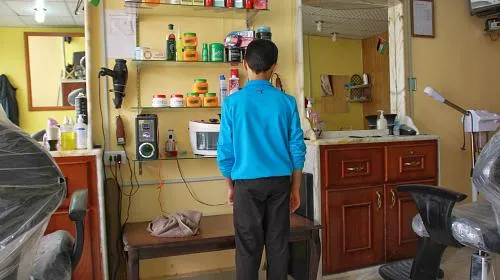 Aboud, 12, fled with his family to Mafraq, Jordan six weeks ago. Instead of attending school, he works in a barber shop from 9:00 in the morning until 10:30 at night, sweeping the floor and cleaning scissors. His 13-year-old brother must work as well to help make ends meet.
