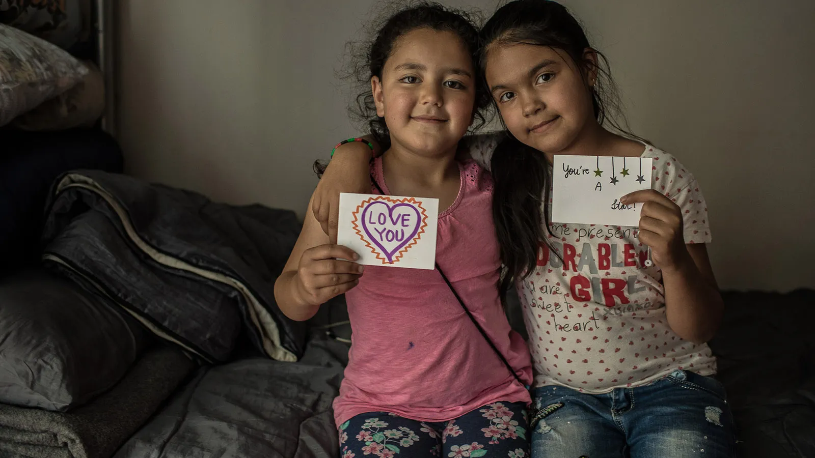 Two girls share the letters they received as part of a letter exchange between American students and international refugees.