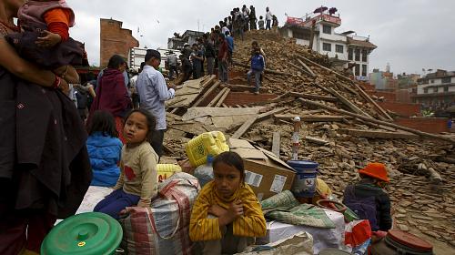 People sit With their belongings outside a damaged temple in Bashantapur Durbar Square after a major earthquake hit Kathmandu , Nepal April 25 , 2015. A shallow earthquake measuring 7.9 magnitude struck west of the ancient Nepali capital of Kathmandu on S