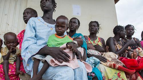 Mulheres se reúnem com seus bebês no Primary Health CARE Center em Pagak, Upper Nile, South Sudan para que as crianças possam ser examinadas e, se necessário, tratadas para desnutrição como parte de uma missão conjunta de resposta rápida da CARE, Unicef, PMA e outros ING