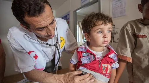 O Dr. Hassan Zebadin (44), um dos muitos funcionários contratados para ajudar pela Sociedade de Socorro Médico Palestina (PMRS), verifica um menino trazido para a clínica improvisada. Crédito da foto: Alison Baskerville / Care