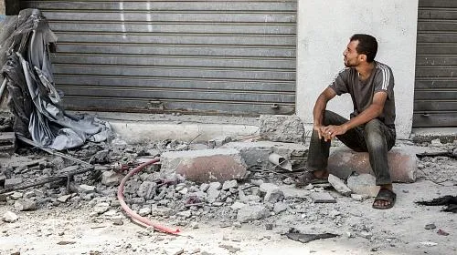 A man sits outside the home of the Al Yasje family which was destroyed in an Israeli airstrike in the Jabalaya district of Gaza.
