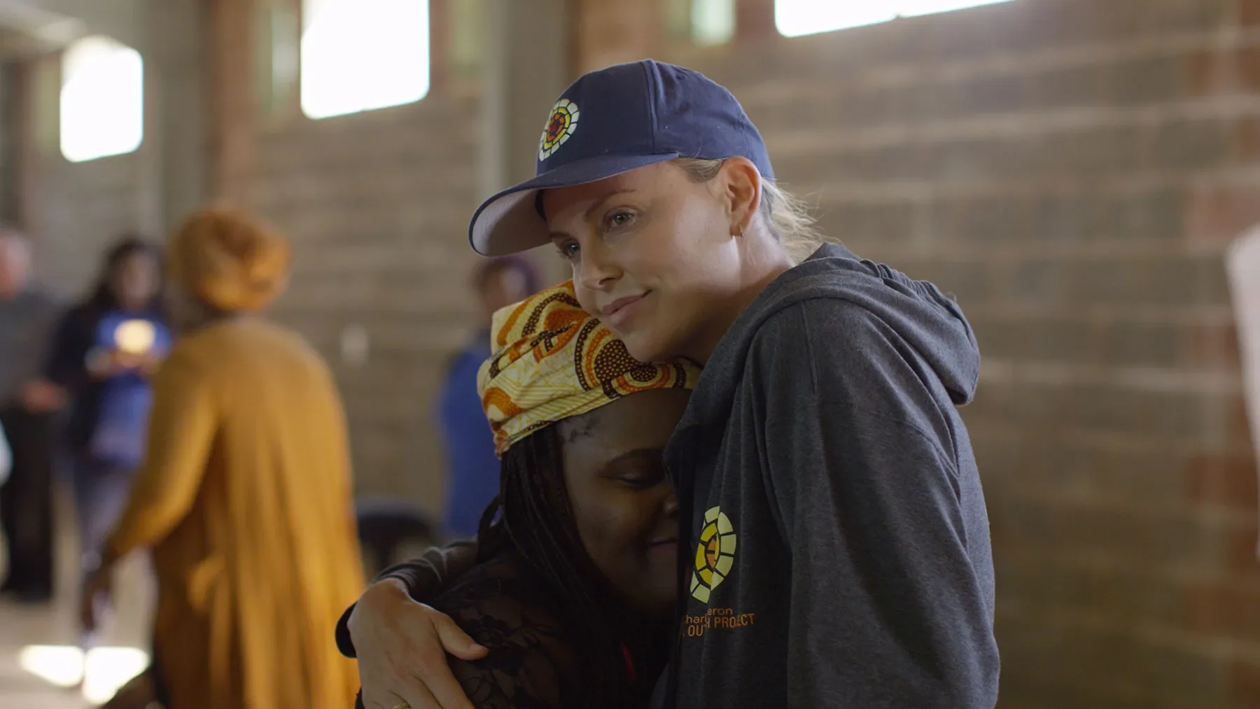 Charlize Theron hugs a young woman.