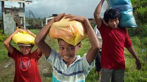 Boys carry rice and other food home after a CARE distribution in the Philippines.