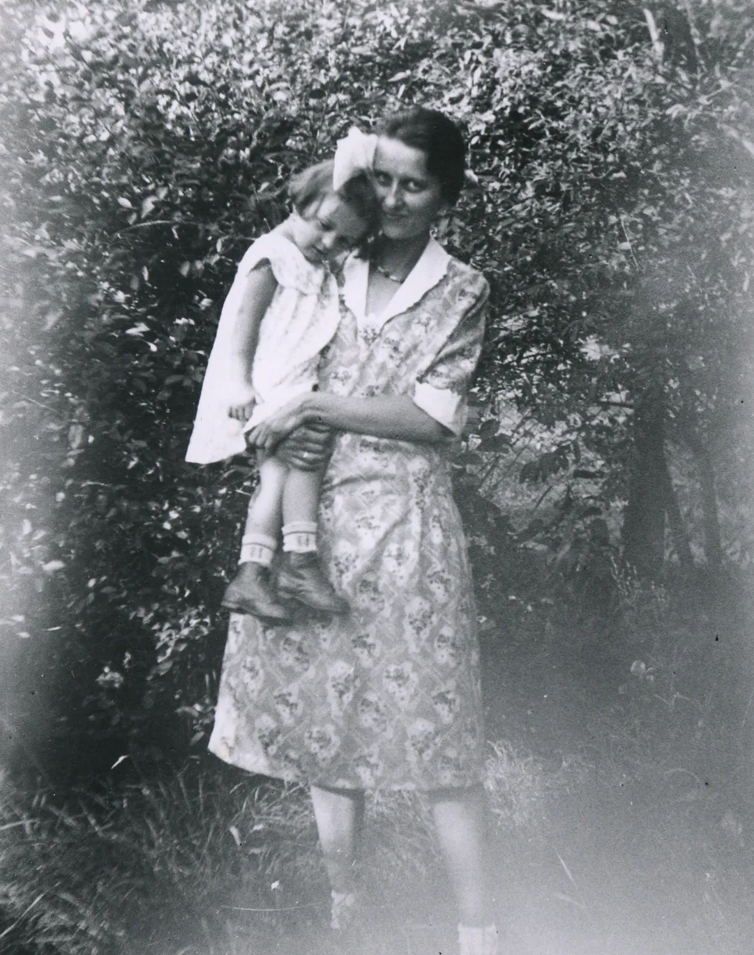 Una mujer con un vestido sostiene a una niña pequeña.