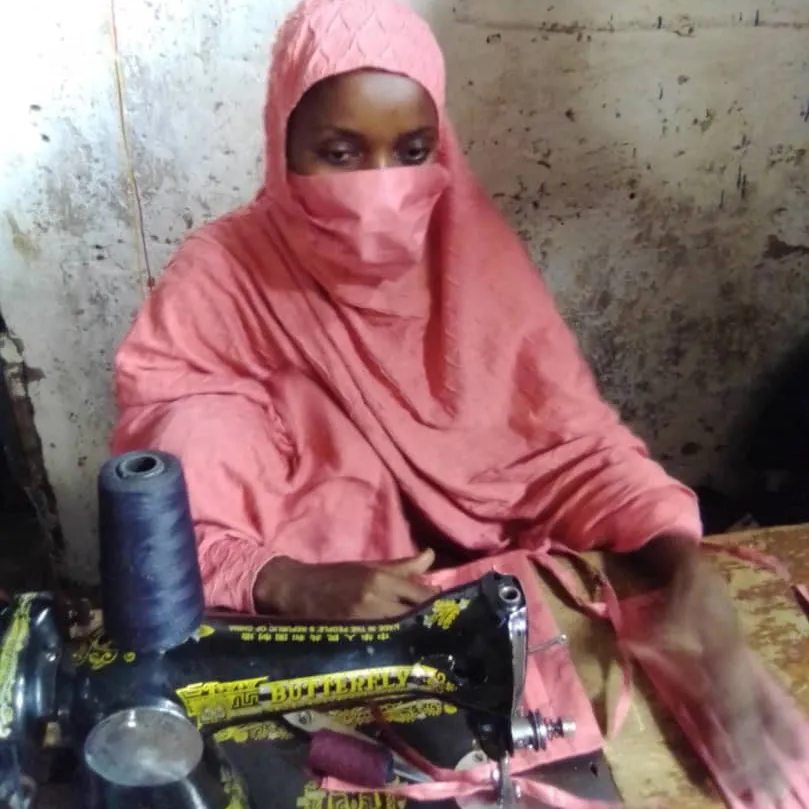 A woman in a mask sews masks with a sewing machine in Niger.