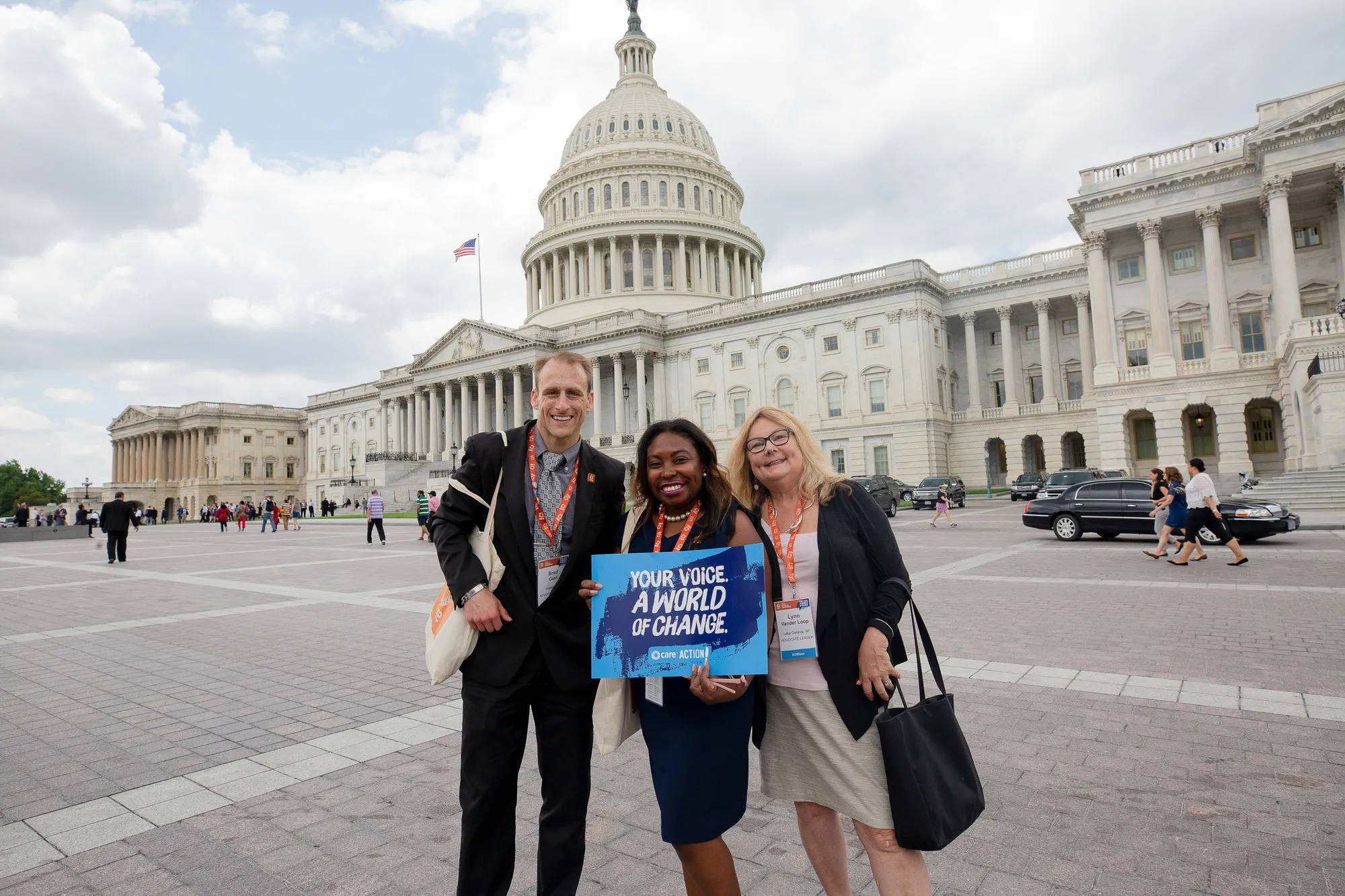 Trois personnes se tiennent devant le Capitole américain. On tient un signe qui lit