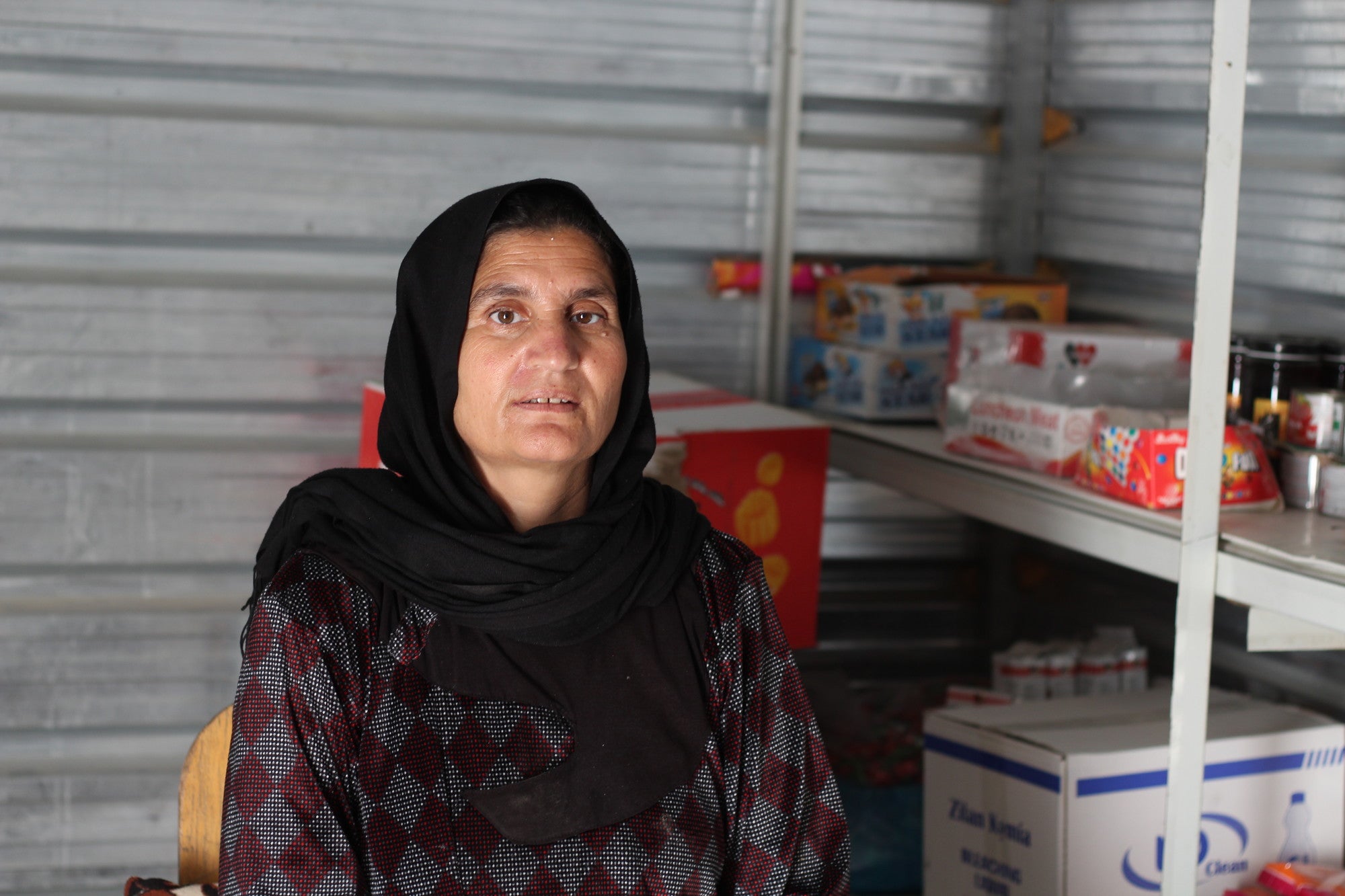 Uma mãe iraquiana está sentada em sua pequena loja no norte do Iraque.