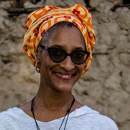 A woman wearing sunglasses and an orange hair wrap.