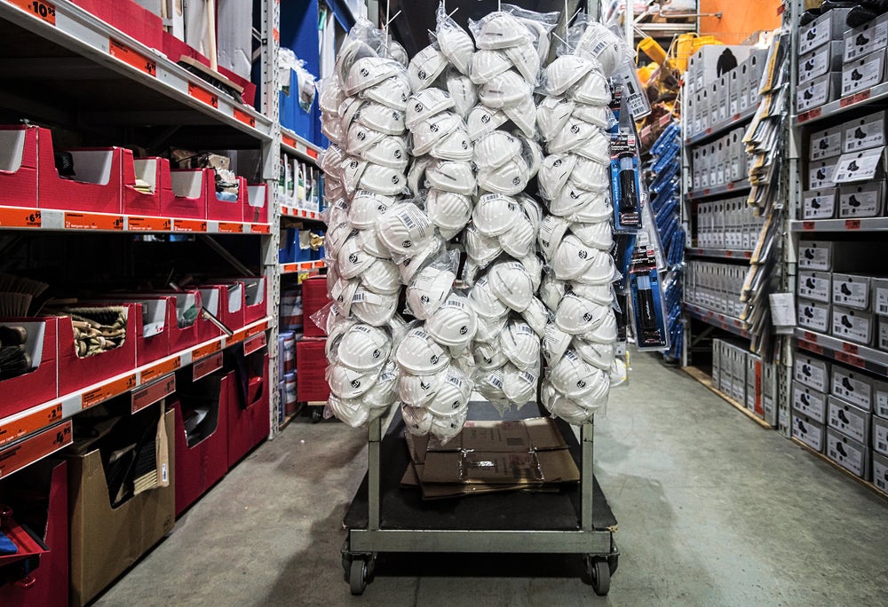 A cart of white safety helmets in the middle of a warehouse aisle.