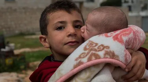 A boy, displaced from Aleppo, clutches his cousin. He and his family now live in a camp in Idlib, in northwestern Syria. CREDIT: Syria Relief/CARE
