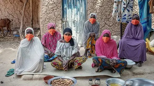 Women continue working outside their home in Niger. Since COVID-19, it has become much harder for them to make a profit off of their peanut plants, so they are often unable to afford basic necessities like food. Photo by Ollivier Girard/CARE