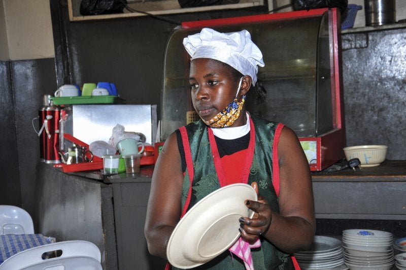 In this photo taken Saturday, June 20, 2020, Rebecca Nakamanya works at a restaurant near a bus terminal in capital Kampala, Uganda. The COVID-19 pandemic means that millions of women in Africa and other developing regions could lose years of success in contributing to household incomes, asserting their independence and expanding financial inclusion. (AP Photo/Ronald Kabuubi)