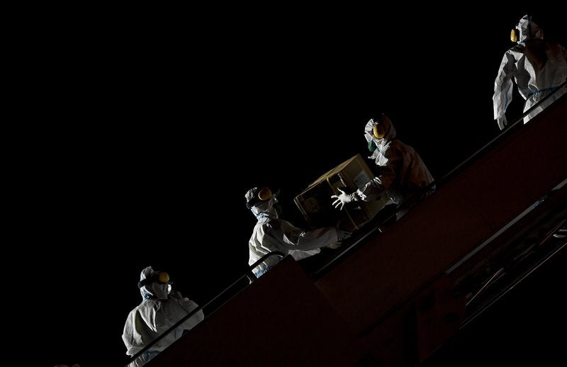In this March 30, 2020, file photo, Venezuelan workers wearing protective face masks and suits as a preventive measure against the spread of the coronavirus unload boxes of humanitarian aid as medical supplies and specialists from China arrive to Simon Bolivar International Airport in La Guaira, Venezuela. A new snapshot of the frantic global response to the coronavirus pandemic shows some of the world's largest government donors of humanitarian assistance are buckling under the strain and overall aid commitments have dropped by a third from the same period last year. (AP Photo/Matias Delacroix, File)