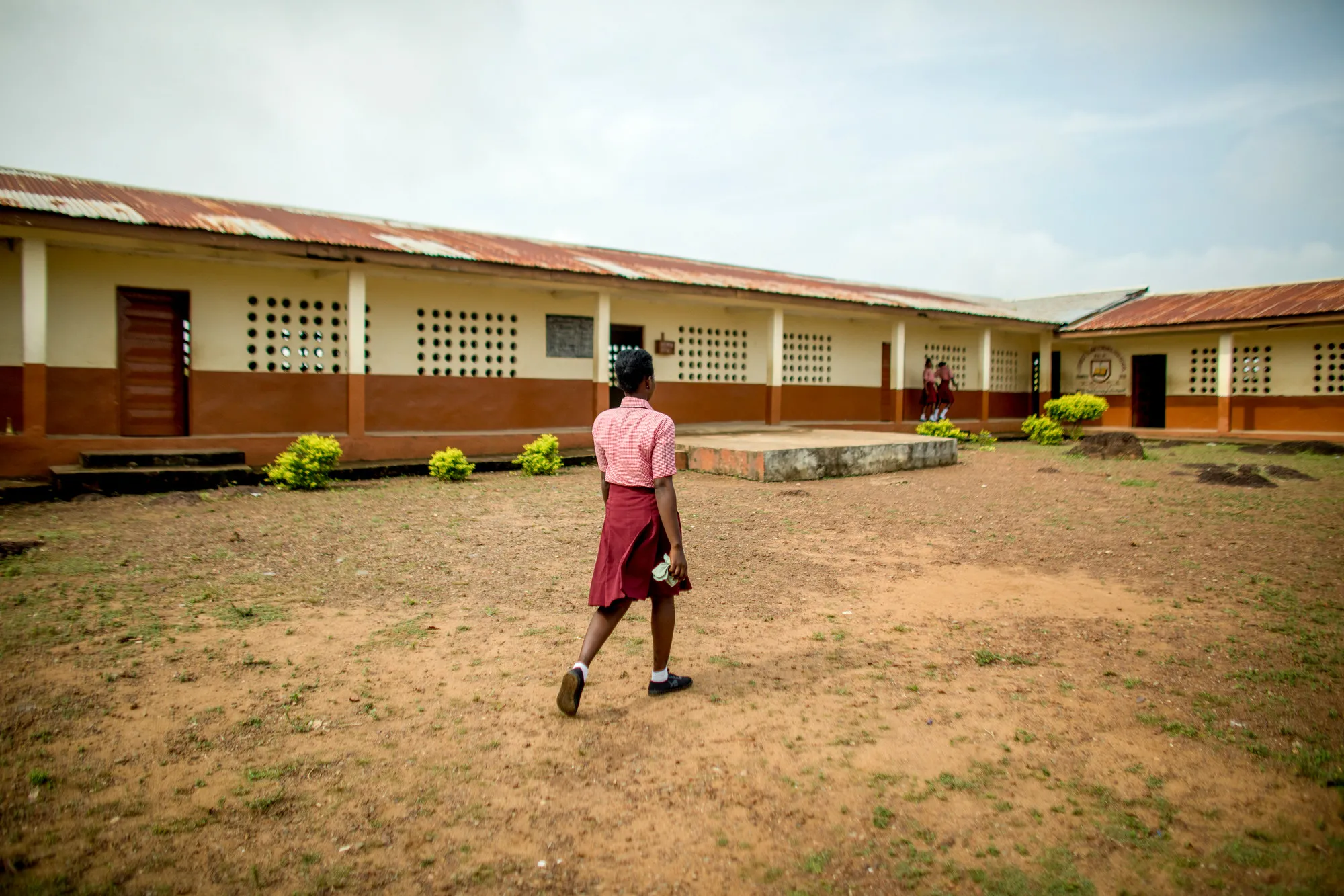 A girl walks in the dirt courtyard of a school in Sierra Leone.