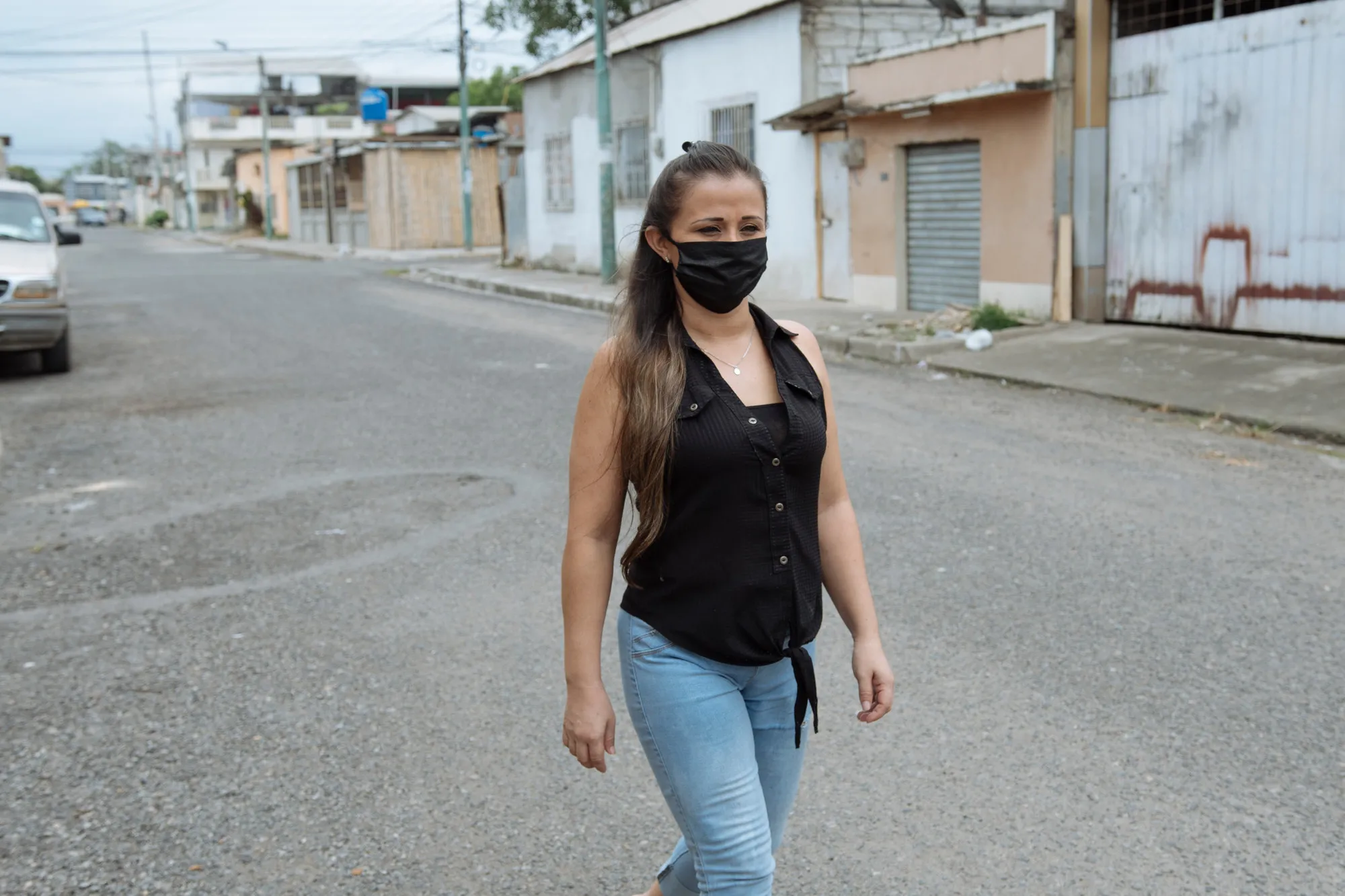 A woman in a face mask walks in an empty city street.