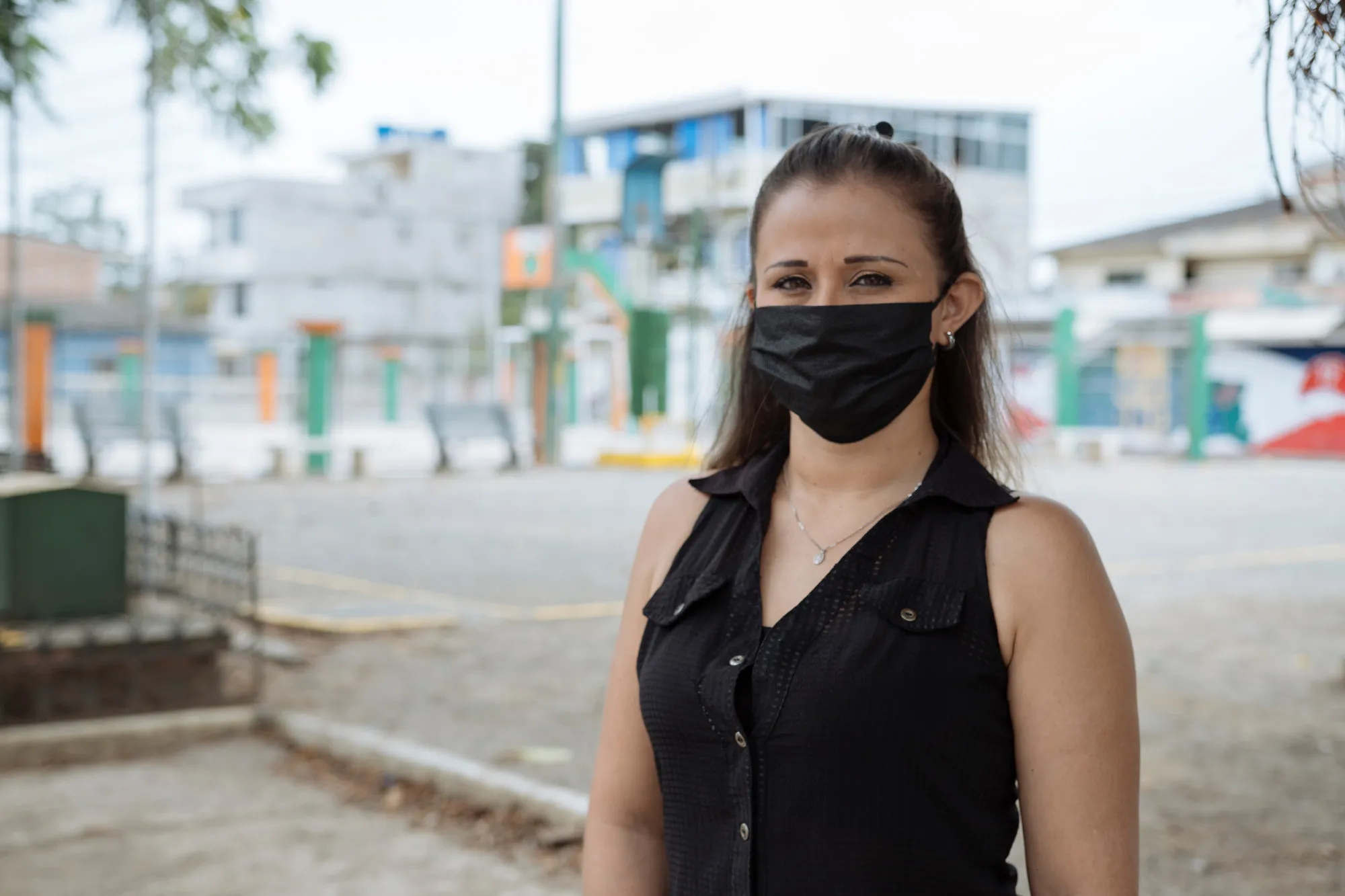 A woman in a face mask stands on a city street.