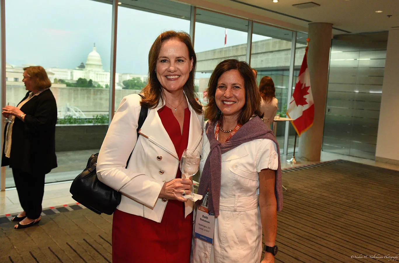 Michéle Flournoy enjoys a glass of water while standing next to Beth Solomon.