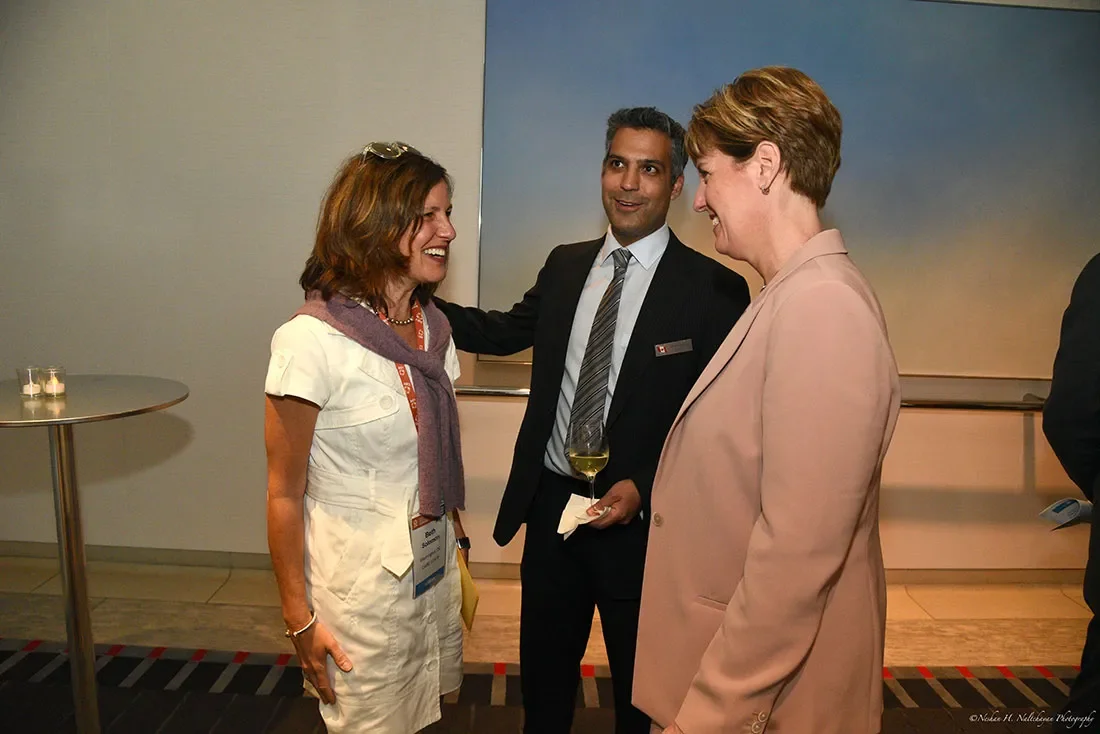Beth Solomon, quien trabaja en CARE, habla con la Ministra Marie-Claude Bibeau y un representante de la Embajada de Canadá.