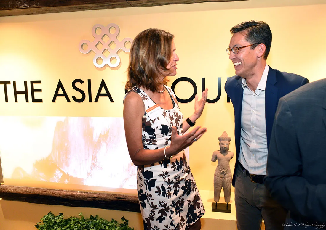Beth Solomon de CARE s'entretient avec Rexon Ryu, partenaire de The Asia Group. Derrière eux se trouve un grand panneau avec le logo de The Asia Group.