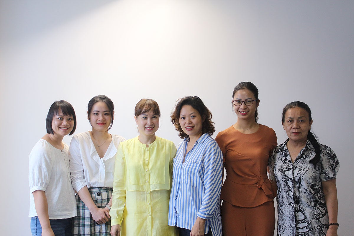 A group of Vietnamese women smile and stand together for a group photo.