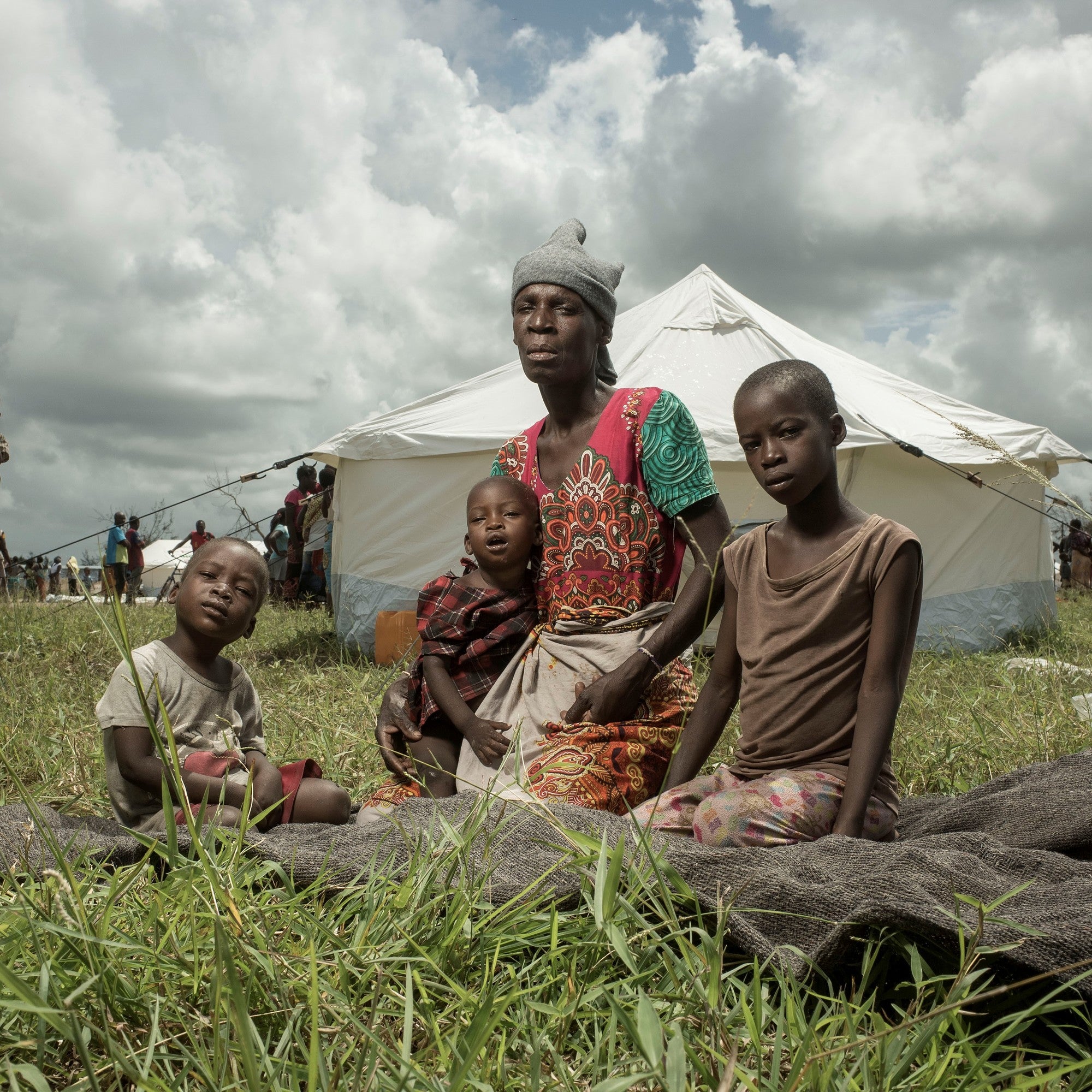 A mother and three of her children sit infant of a temporary shelter.