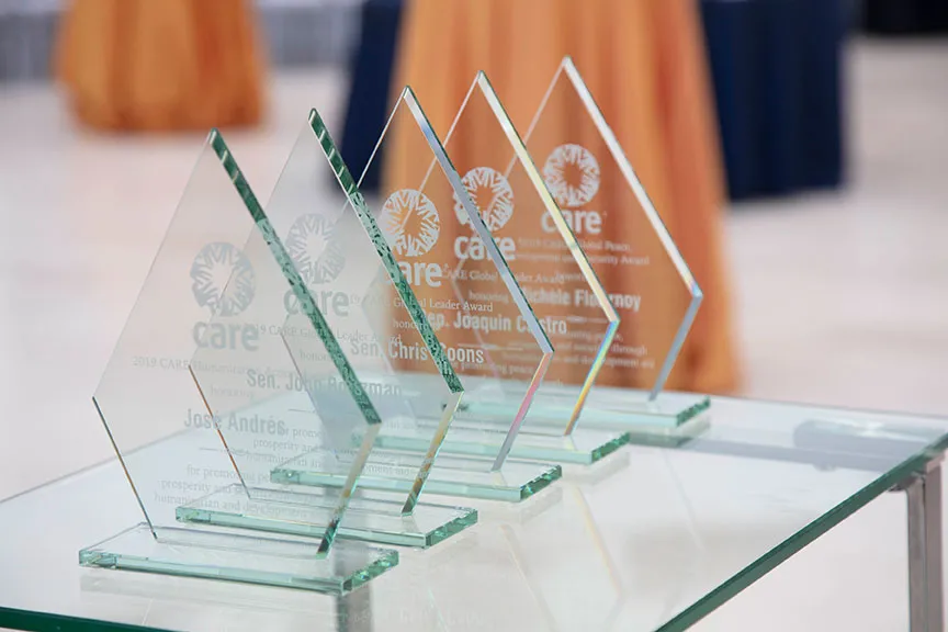 Uma imagem em close-up dos prêmios CARE Global Leader, todos de vidro com letras brancas.