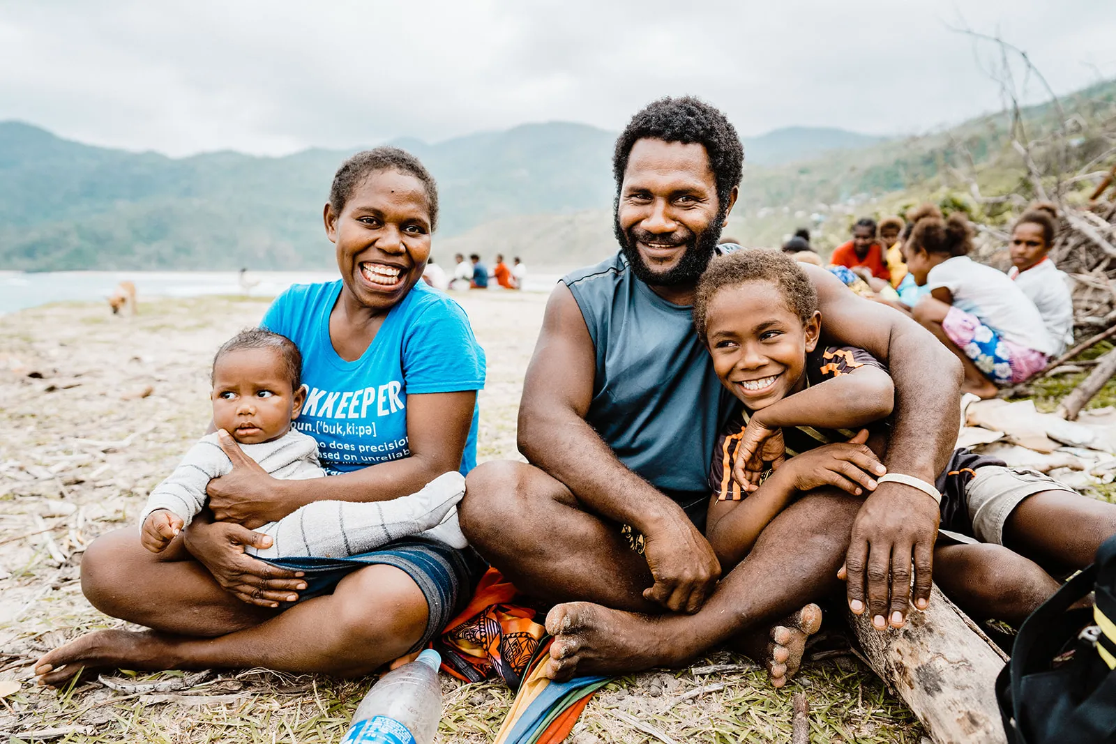 A family smiles while sitting on a beach