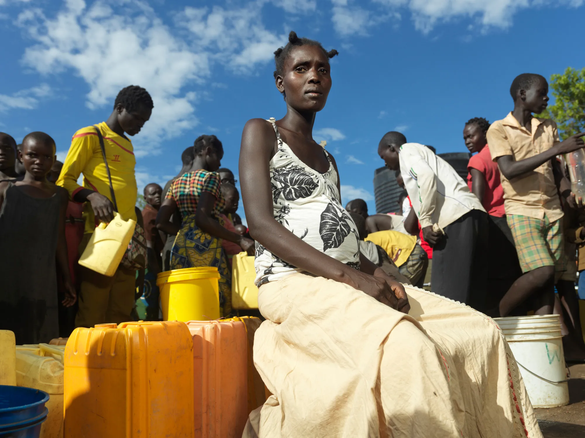 A woman sits on jerry cans in a crowd of people