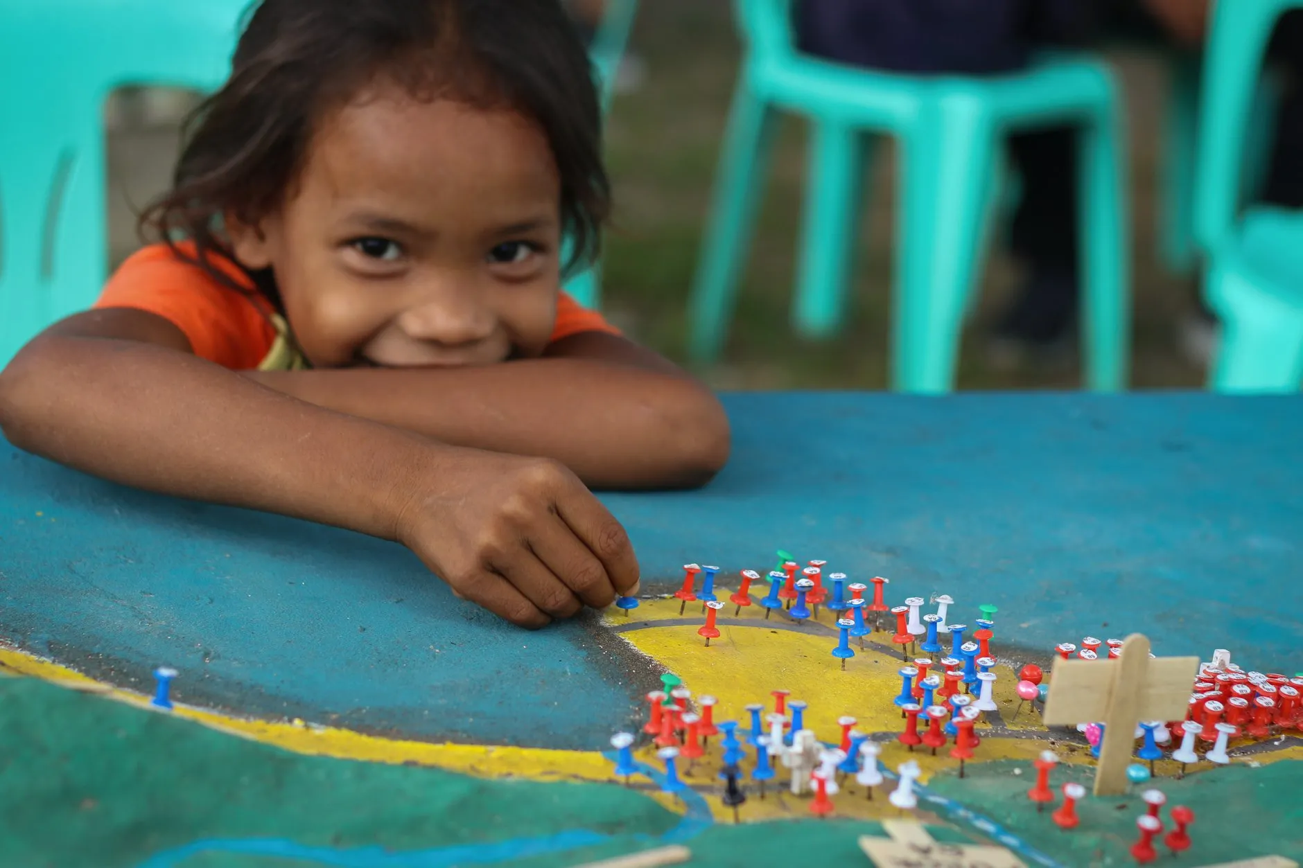 A girl smiles while looking at a map on a table