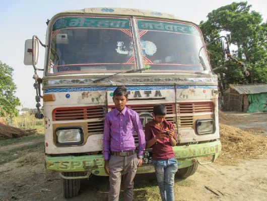 Two young boys stand in front of a van.