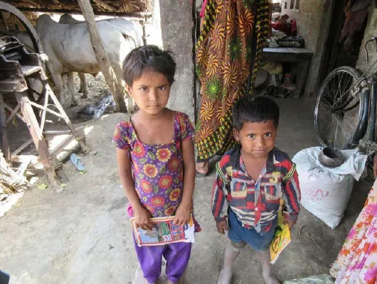 Two young children, a girl and a boy, hold books in their hands.