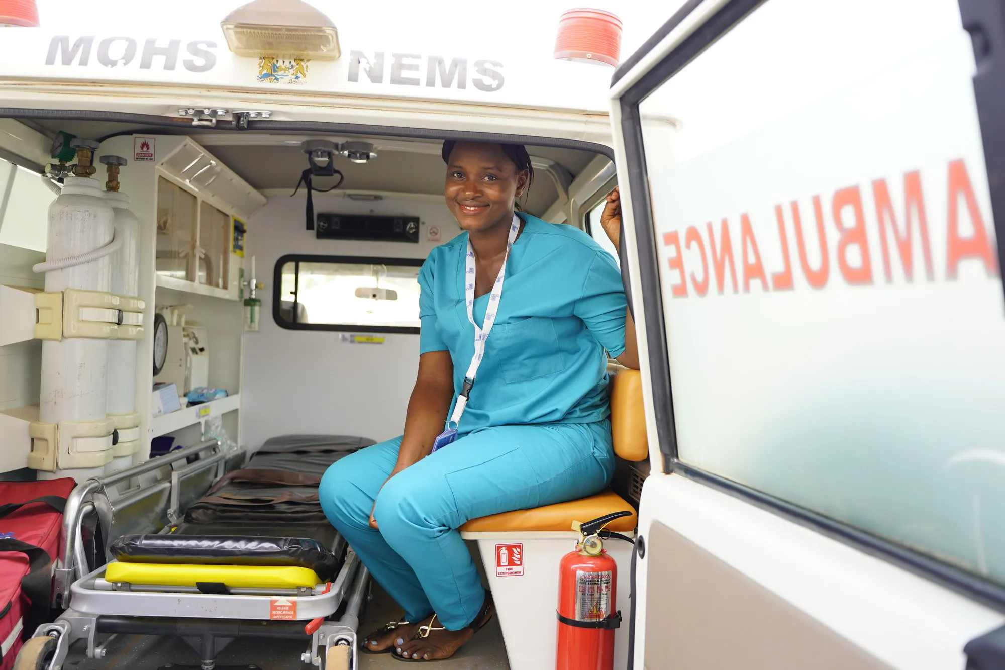Uma trabalhadora de saúde está sentada na parte de trás de uma ambulância.