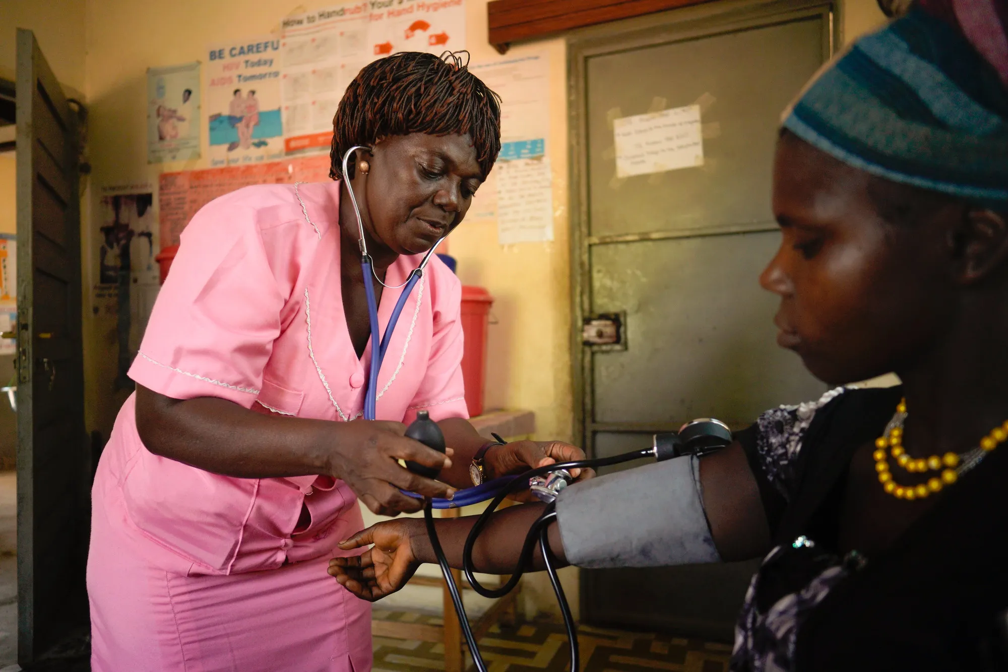 A female health care worker checks the blood pressure of a woman.