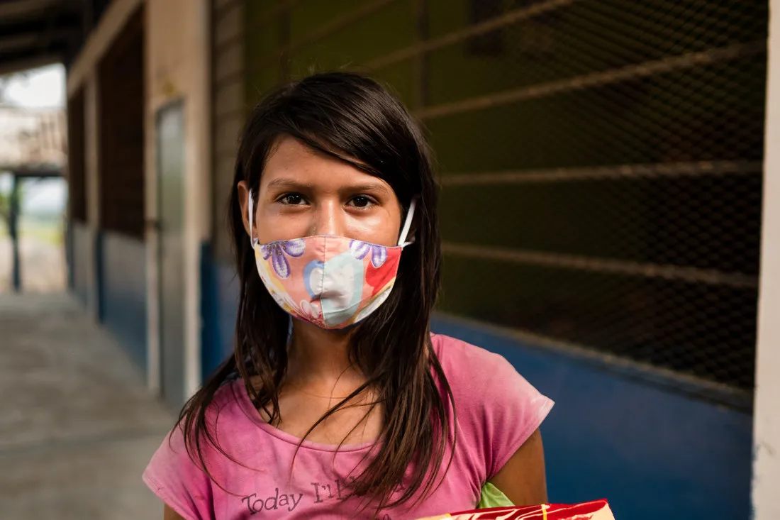 A portrait of a young Honduran woman wearing a floral facemask.