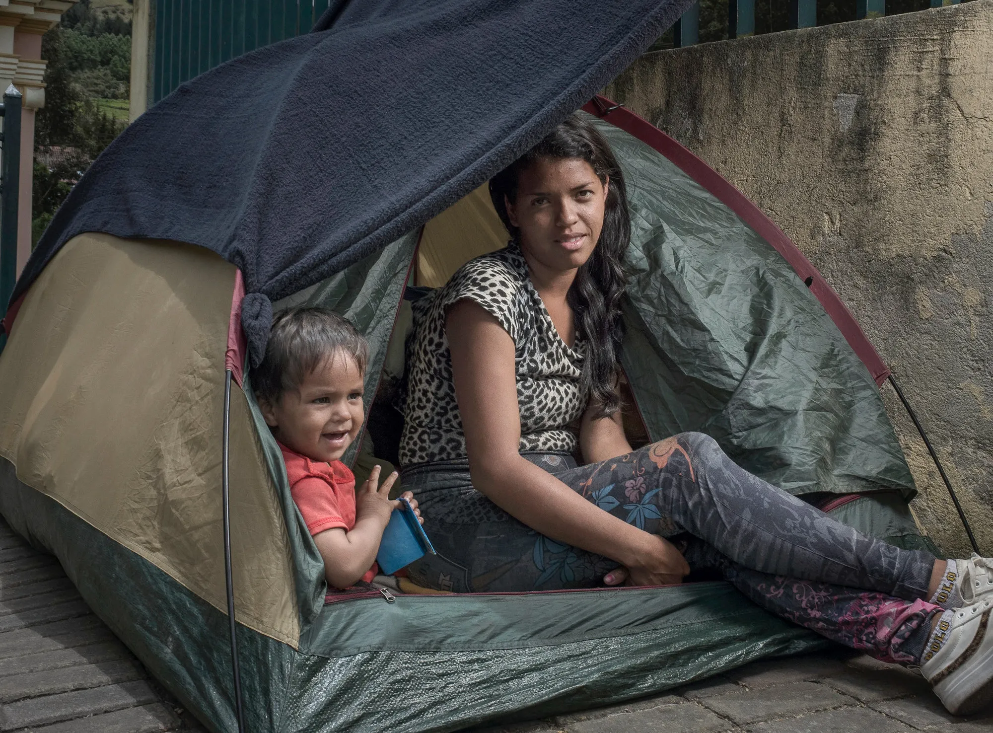 A woman and a child sit in a tent.