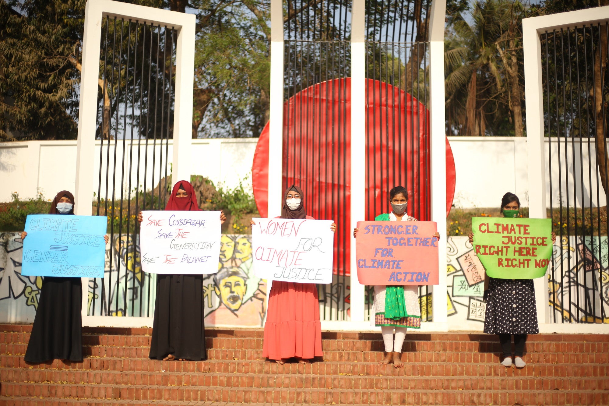 Cinco mujeres sostienen carteles de cambio climático.