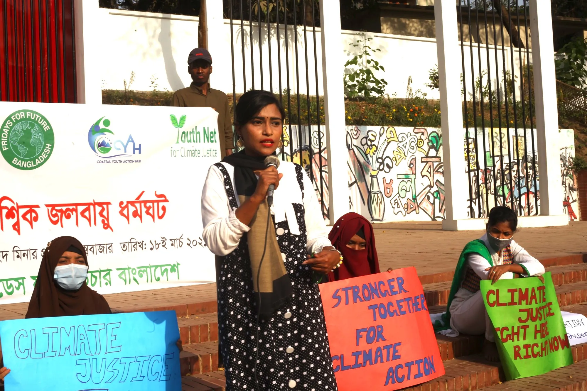 A woman holds a microphone at a climate justice event in Bangladesh.