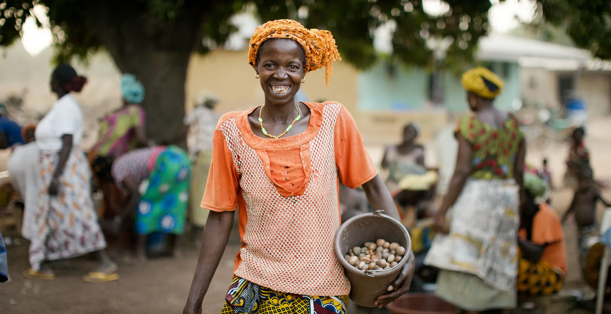 A woman holding a bucket smiles.