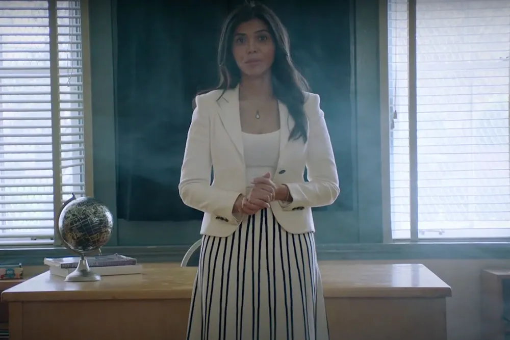Sheila Shah stands in front of a school desk.