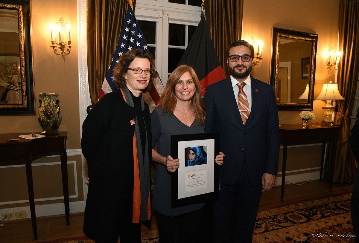 A woman holding a CARE award stands between CARE CEO Michelle Nunn and Ambassador Hamdullah Mohib