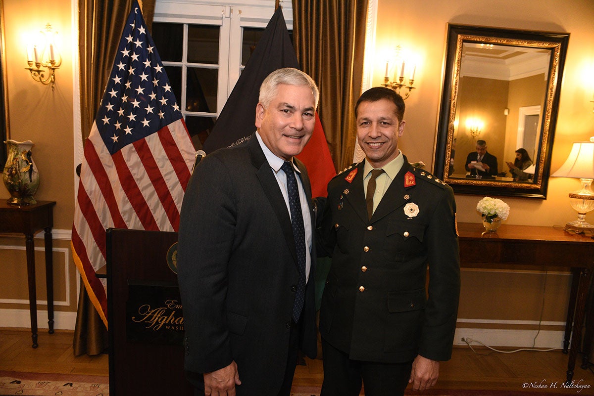Two men, one in a black suit and another in a military formal attire, stand together