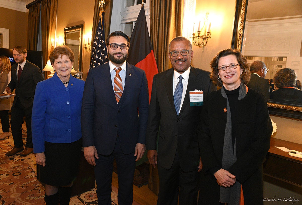 Ambassador Hamdullah Mohib and CARE CEO Michelle Nunn stand with a woman in a blue jacket and a man in a black suit