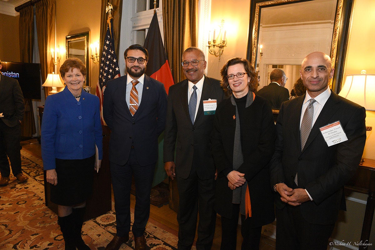 Ambassador Hamdullah Mohib and CARE CEO Michelle Nunn stand with a woman in a blue jacket, and two men in black suits