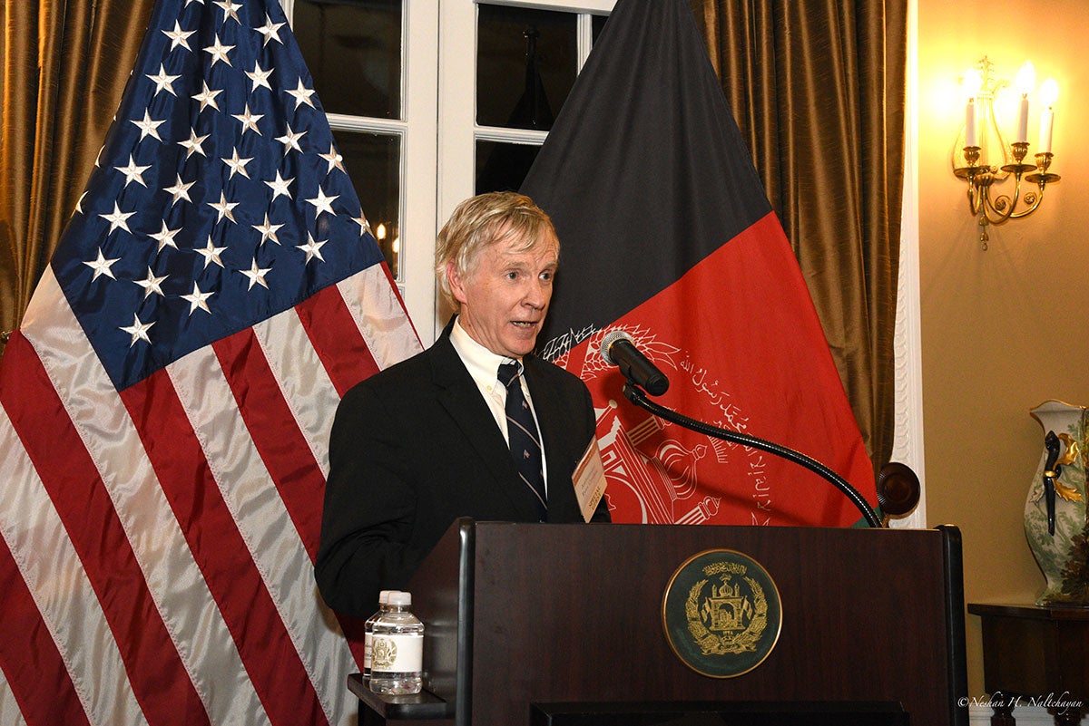 Ambassador Ryan Crocker is giving a speech with the US and Afghan flags in the background